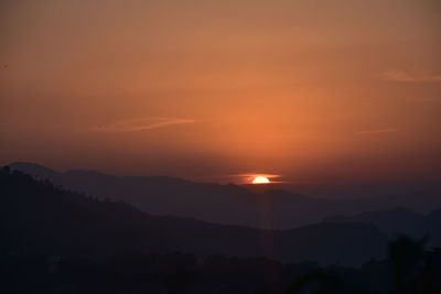 Scenic view of silhouette mountains against romantic sky at sunset