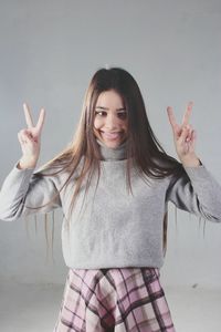 Portrait of woman making a face while gesturing against gray background