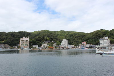 Buildings at waterfront against cloudy sky