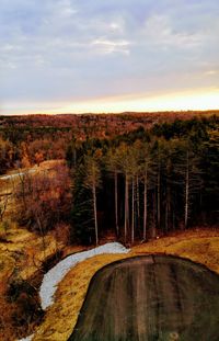 Road by river against sky at sunset