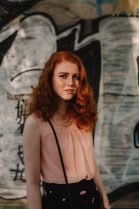 Portrait of young confident woman standing against wall in city  person