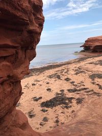 Rock formation on beach against sky