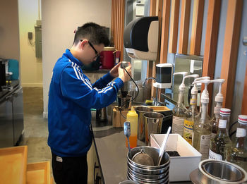Side view of man standing in kitchen