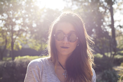 Portrait of young woman in park during sunny day