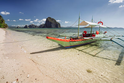 Boat moored on beach against sky