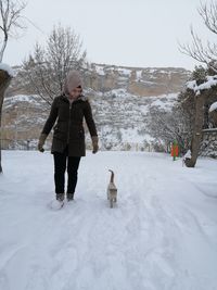 Full length of man with dog on snow during winter