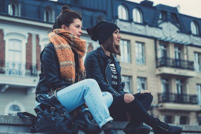 Full length of young woman sitting in city