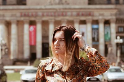 Young woman looking away against building