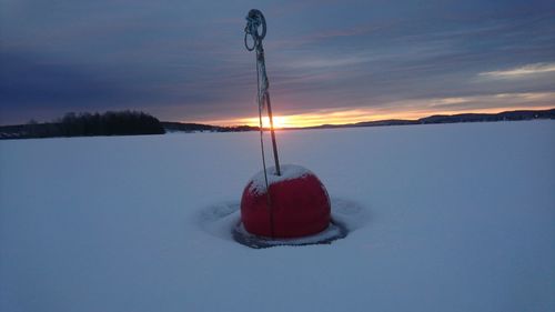 Snow covered landscape against sky during sunset