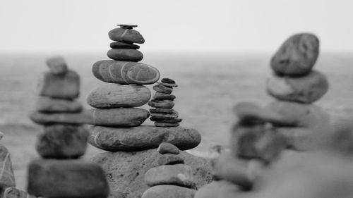 Close-up of stack of stones at beach against clear sky