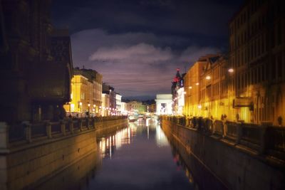 Canal amidst buildings in city at night