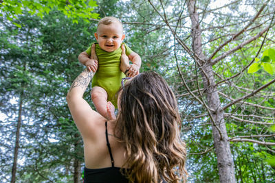 Full length portrait of smiling young woman against trees