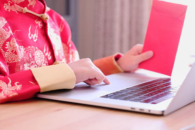 Midsection of woman using mobile phone while sitting on table