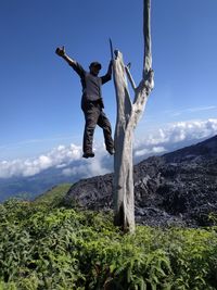 Man jumping in mountains against sky