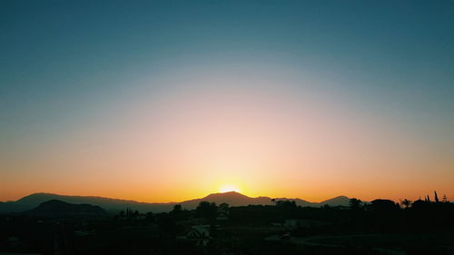 Scenic view of silhouette mountains against clear sky during sunset