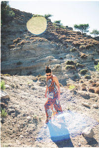 Fashionable woman walking on dirt against rock formation