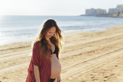 Beautiful young woman standing on beach