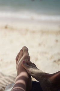 Low section of person resting on sand at beach