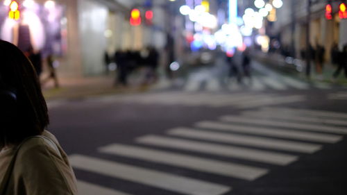 Rear view of woman walking on road at night