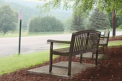 Empty bench on field by trees