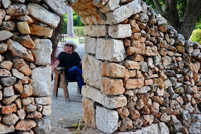 Full length of woman standing against stone wall