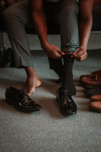 Low section of man wearing socks surrounded by shoes