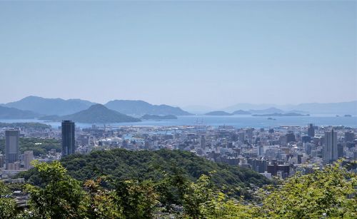 Scenic view of city and mountains against clear sky