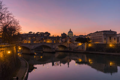 Reflection of illuminated buildings in river at sunset