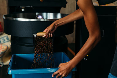 Cropped hands of young woman making coffee beans in shop