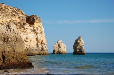 Scenic view of rocky cliff and sea against sky 