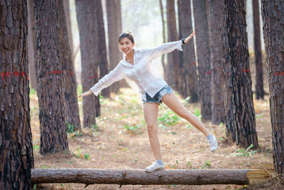 Woman balancing on log in forest