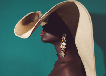 Midsection of black woman wearing large sun hat and statement earrings