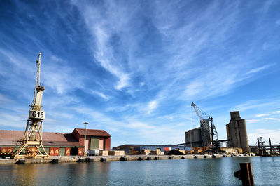 Buildings by river against sky in city