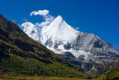 Low angle view of snowcapped mountain against blue sky