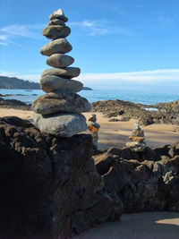 Stack of stones on beach against sky