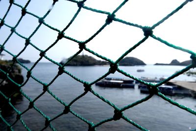 Close-up of chainlink fence against sea