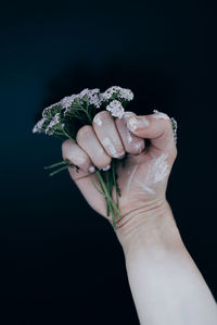 Midsection of woman holding bouquet against black background