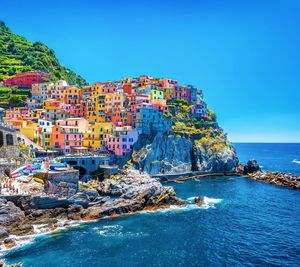 Scenic view of sea by buildings against clear blue sky