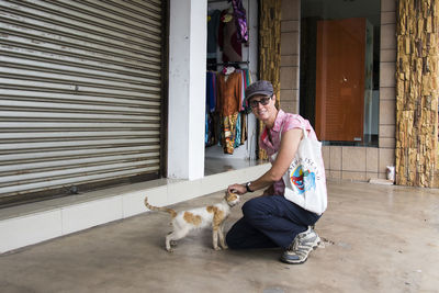 Woman with cat sitting on floor outdoors