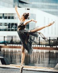 Young woman jumping on pole in city