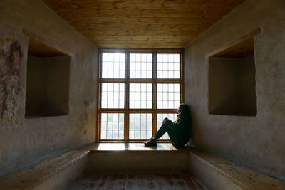 Side view of woman standing in window at home