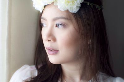 Close-up portrait of thoughtful young woman wearing flowers looking away