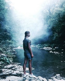 Full length of man standing on rock in forest