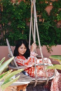 Portrait of smiling woman sitting on swing