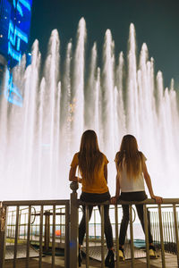 Rear view of women sitting on railing