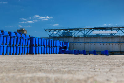 Blue garbage bins on field against sky
