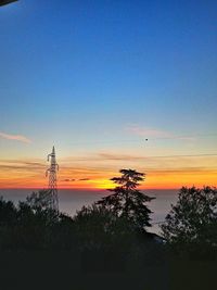 Silhouette trees against dramatic sky during sunset