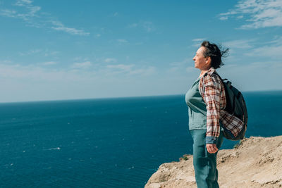 Side view of man standing by sea against sky