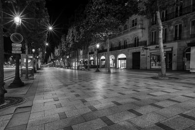 Illuminated street amidst buildings at night