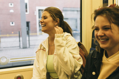 Happy woman laughing while traveling with friend in train